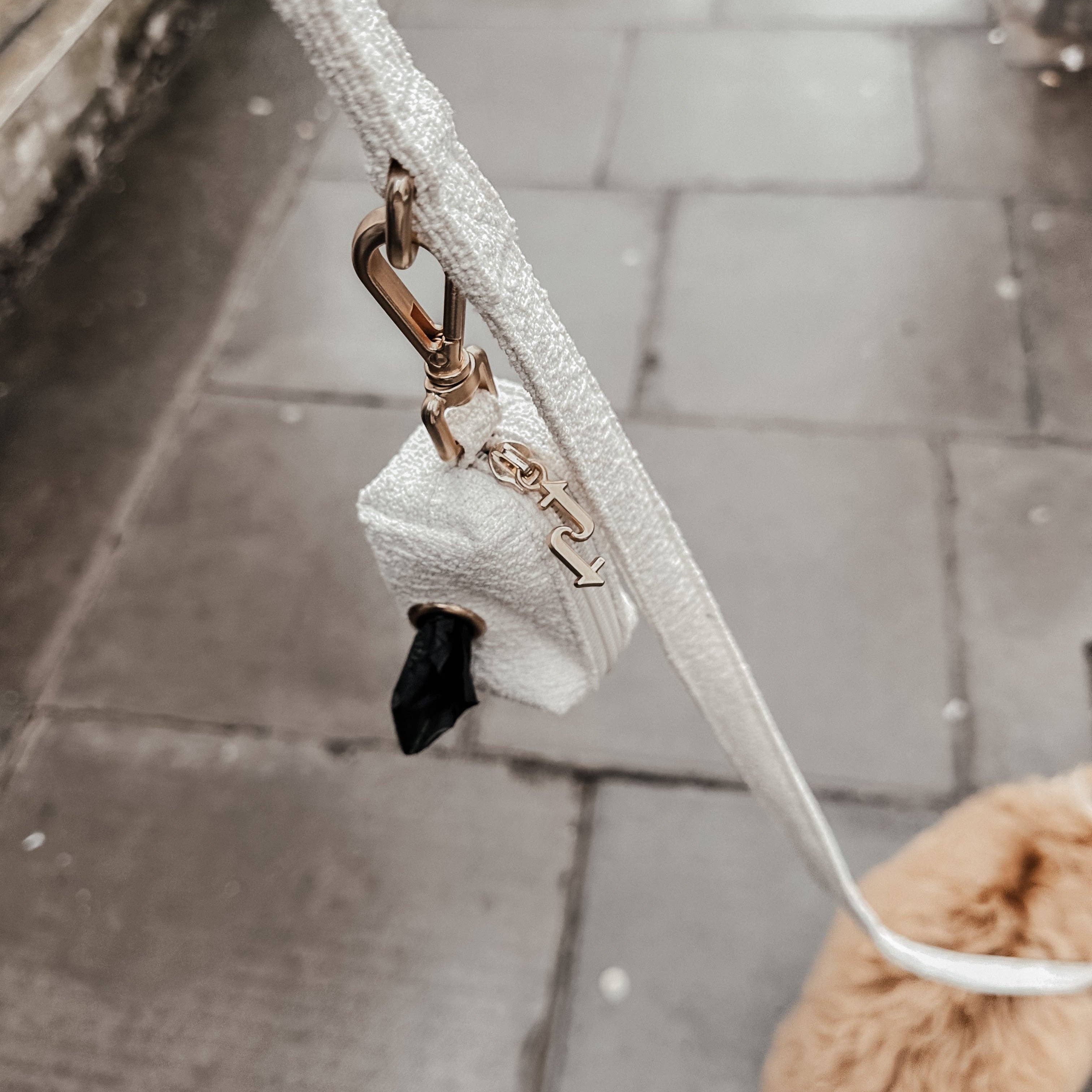 Dog leash with a fluffy dog toy attached, on a sidewalk.