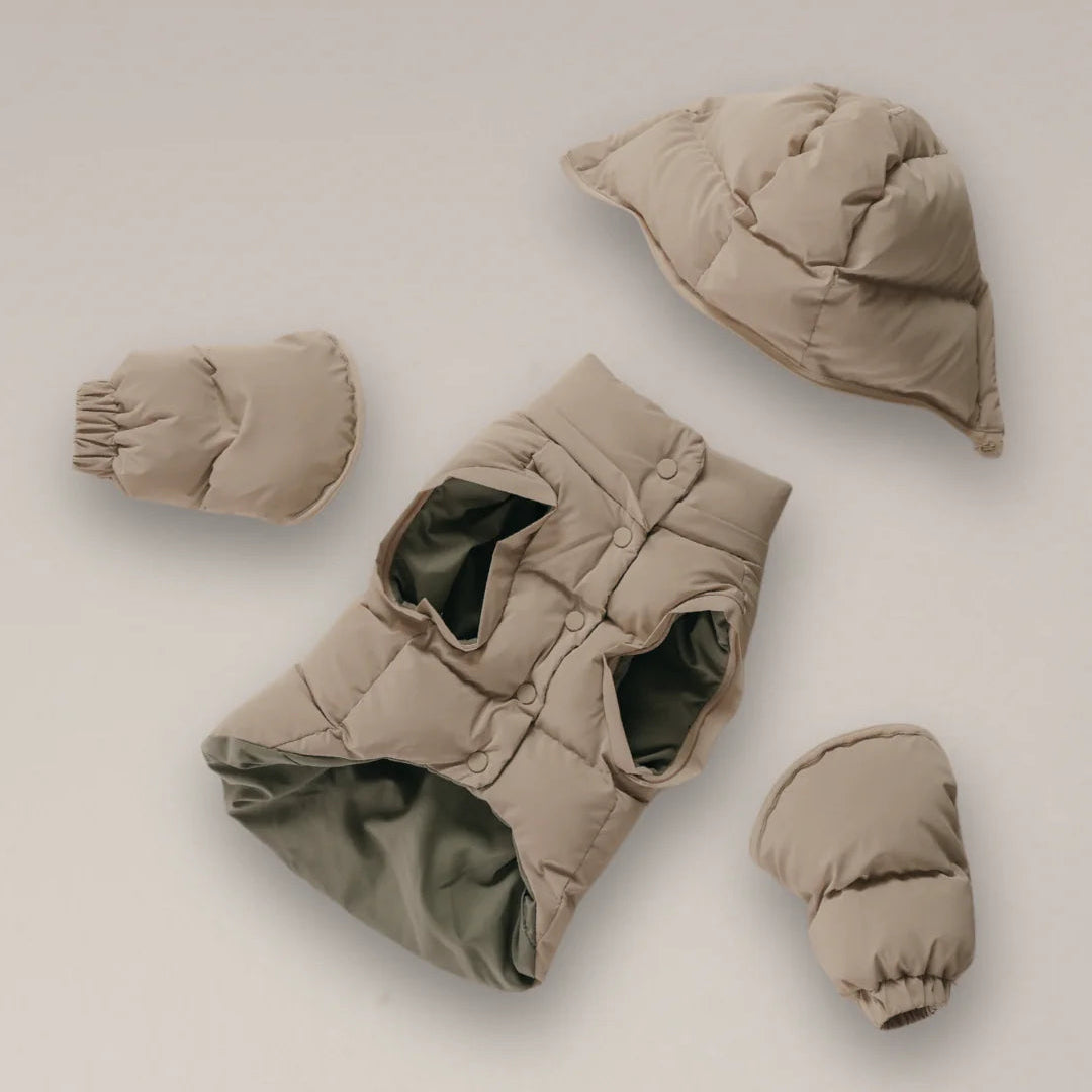 Set of beige baby winter clothing including a jacket, hat, and mittens on a light background