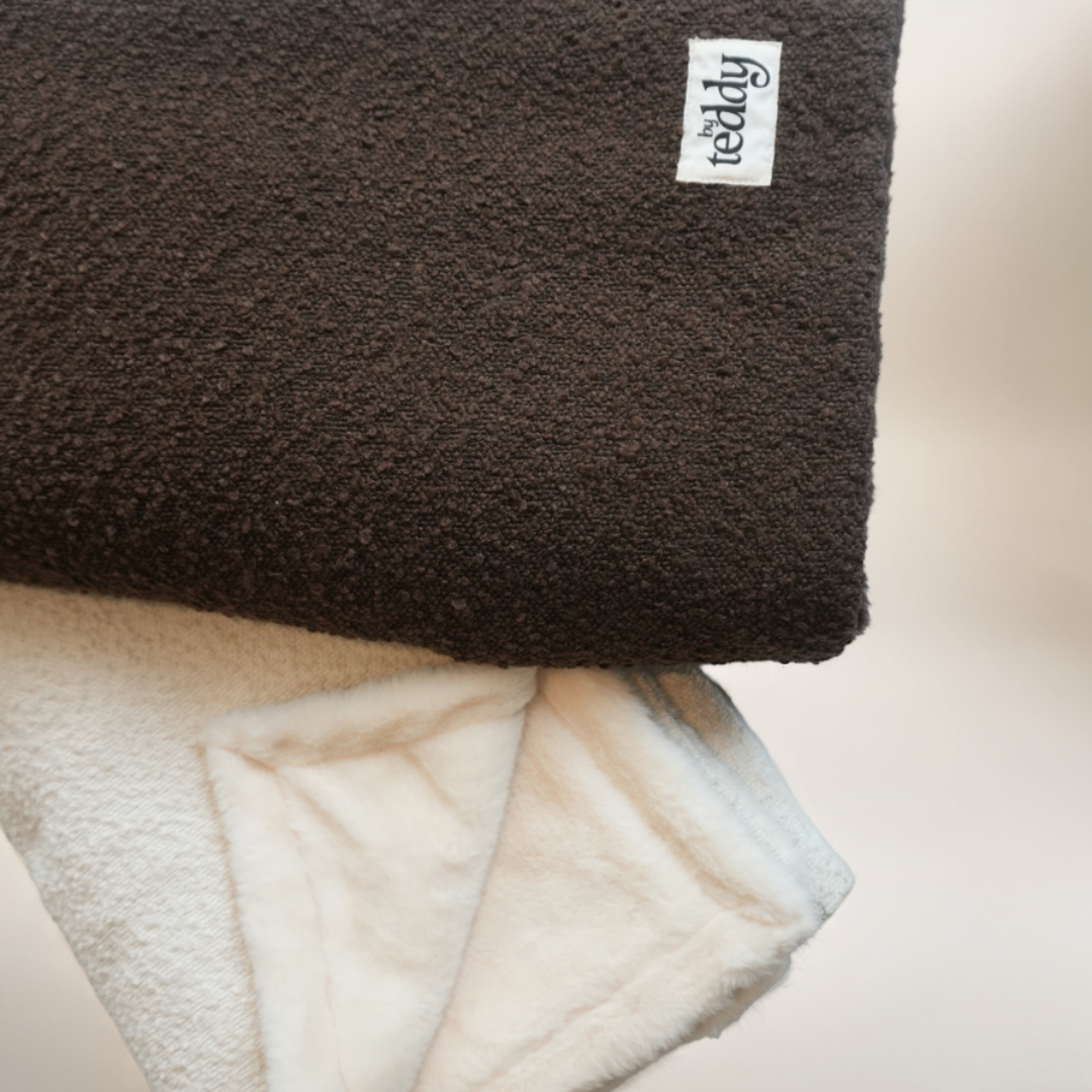 Brown and white fleece blanket with a brand label on a light background