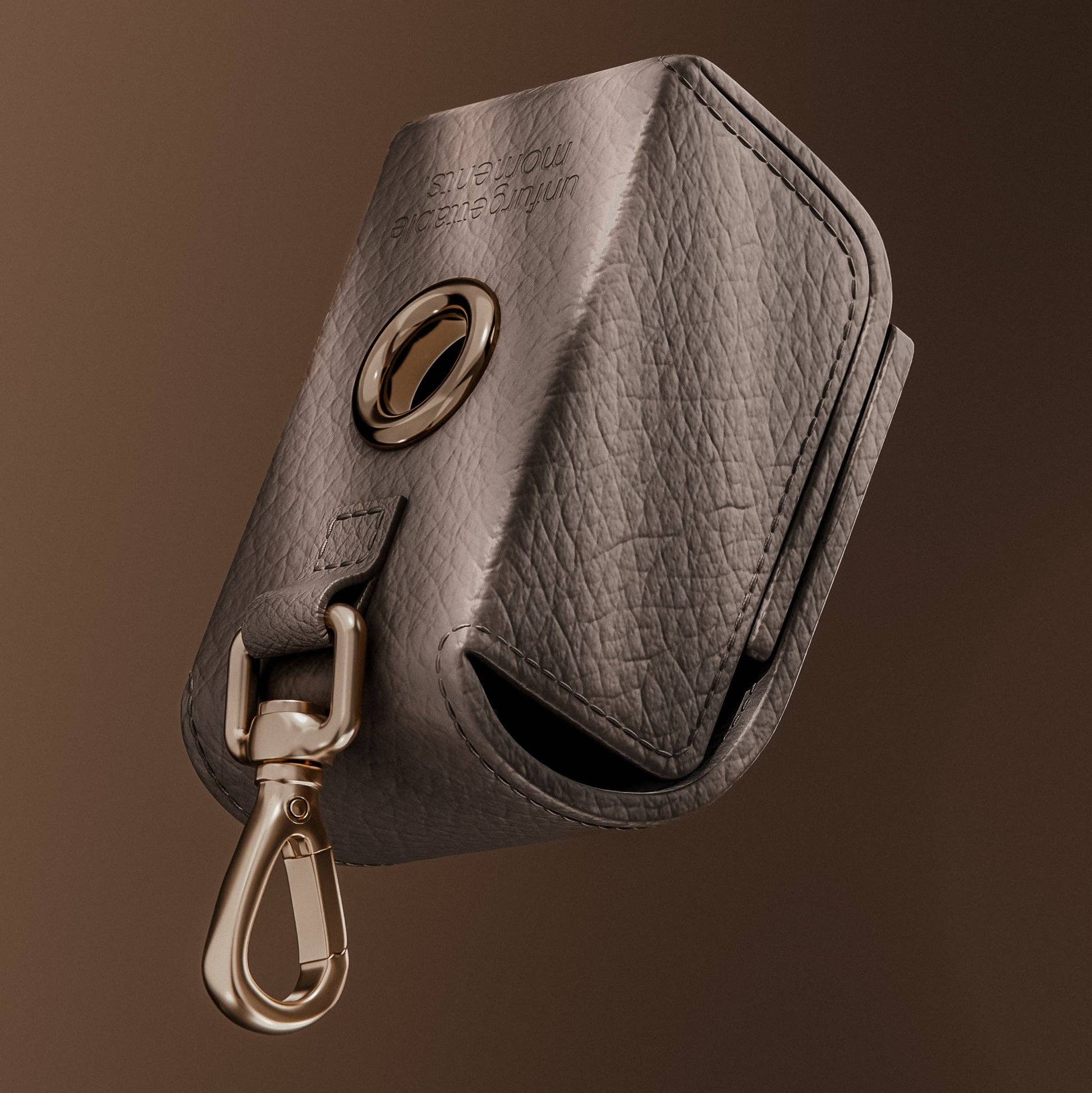 Gray leather key pouch with gold clasp on a brown background