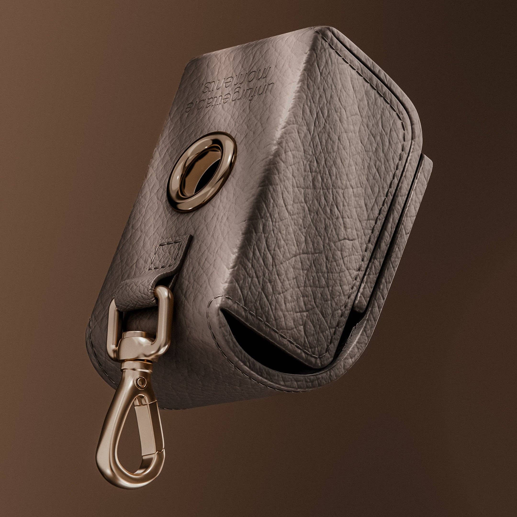 Gray leather key pouch with gold clasp on a brown background