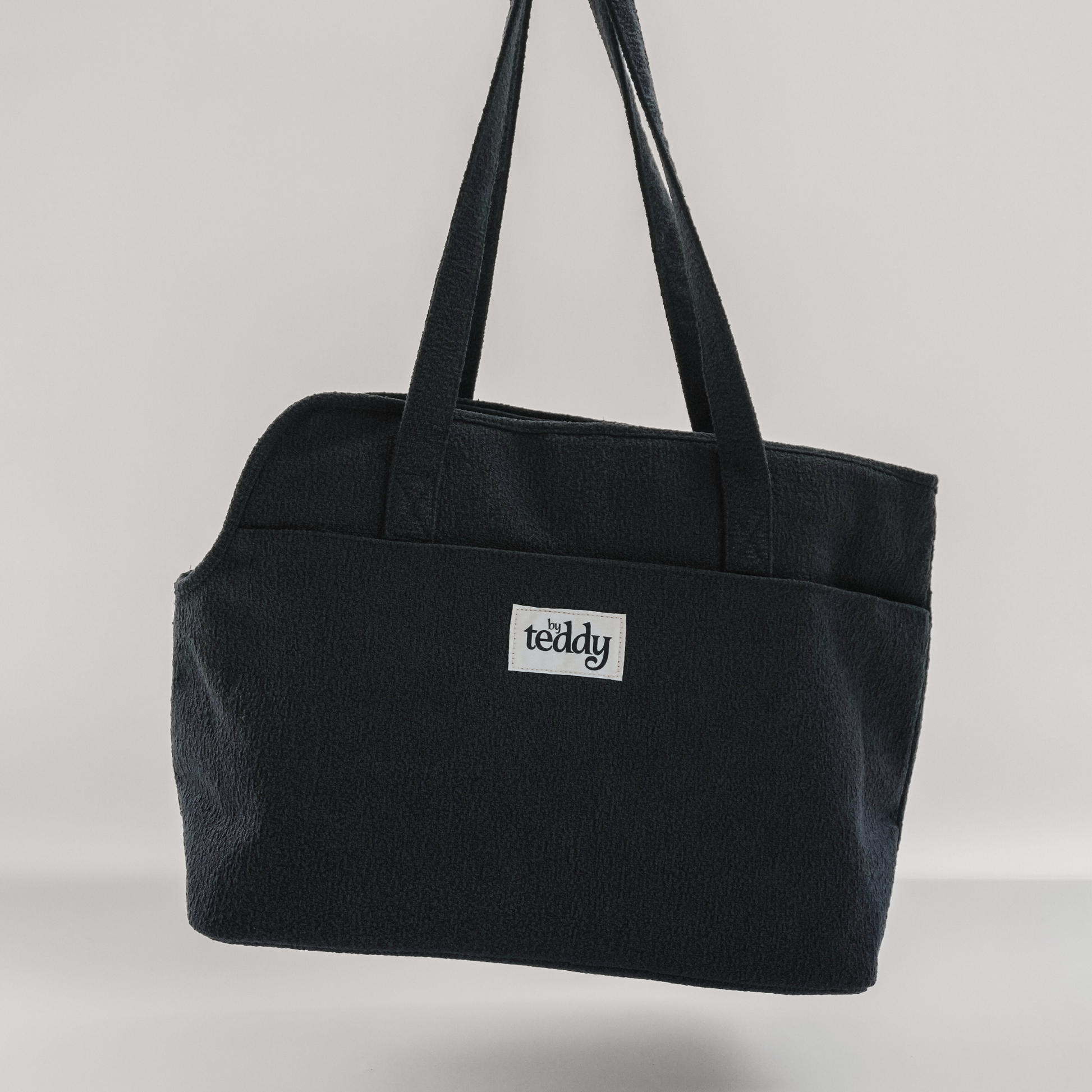 Black tote bag with 'teddy' logo on a light gray background