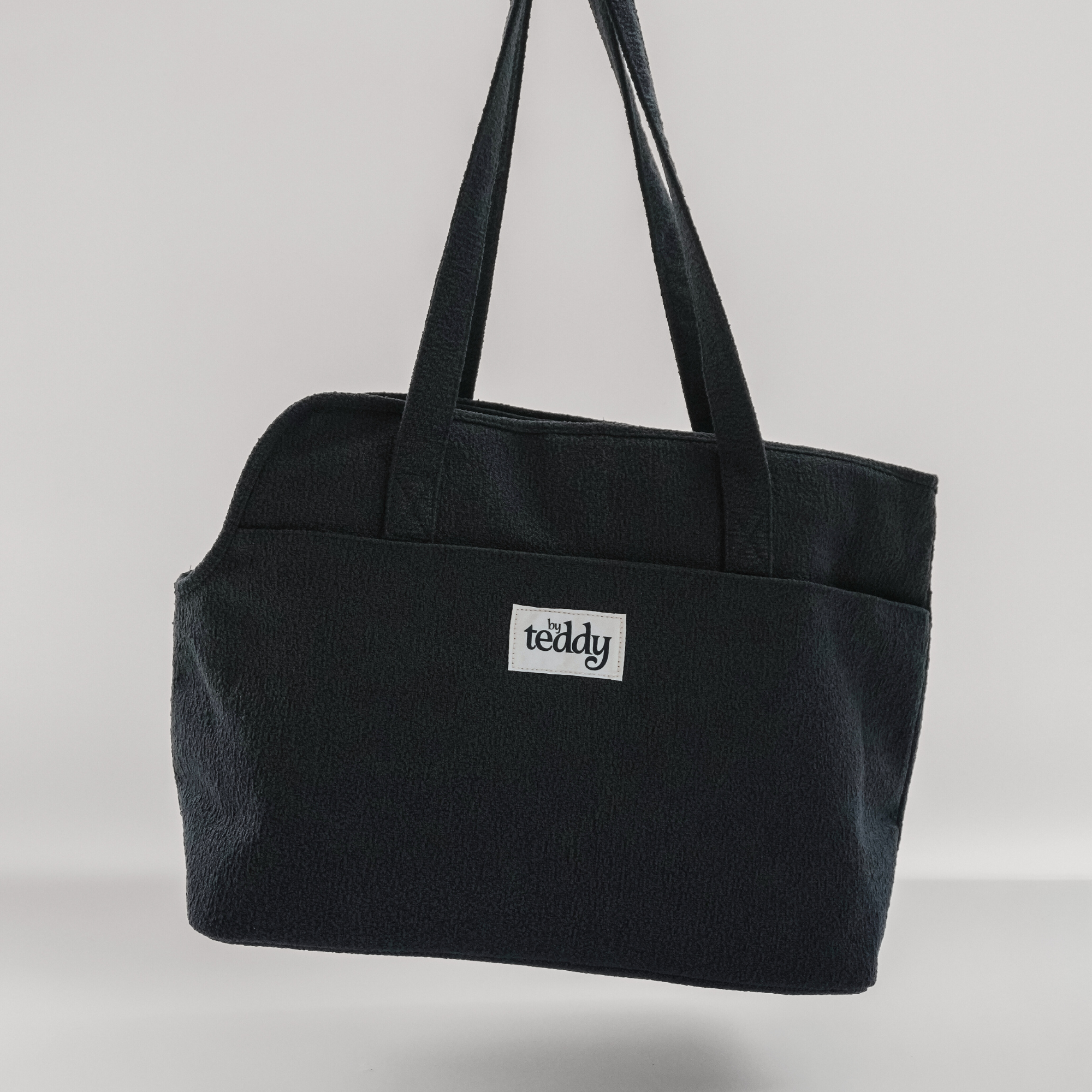 Black tote bag with 'teddy' logo on a light gray background