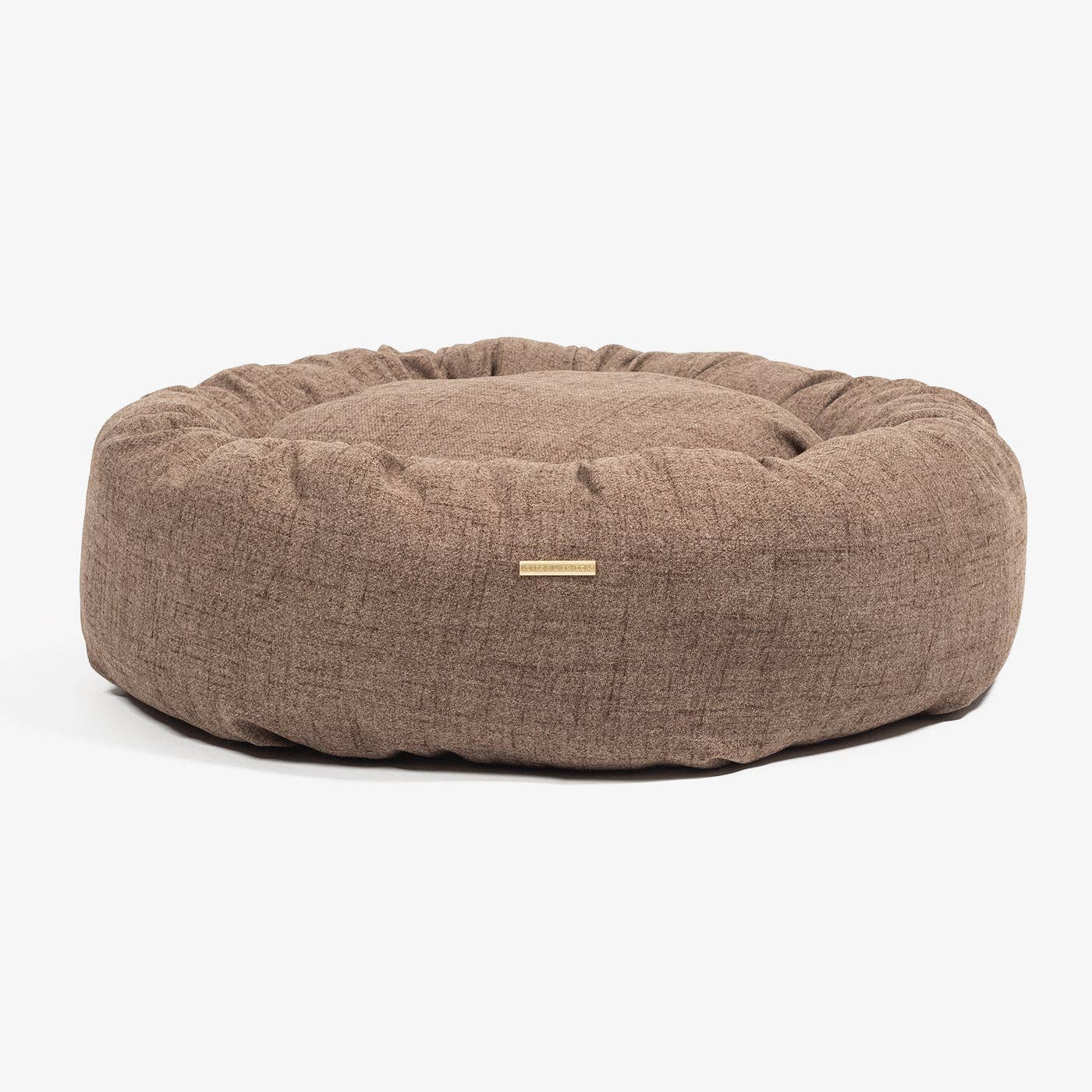 Brown textured dog bed with a brand tag on a white background
