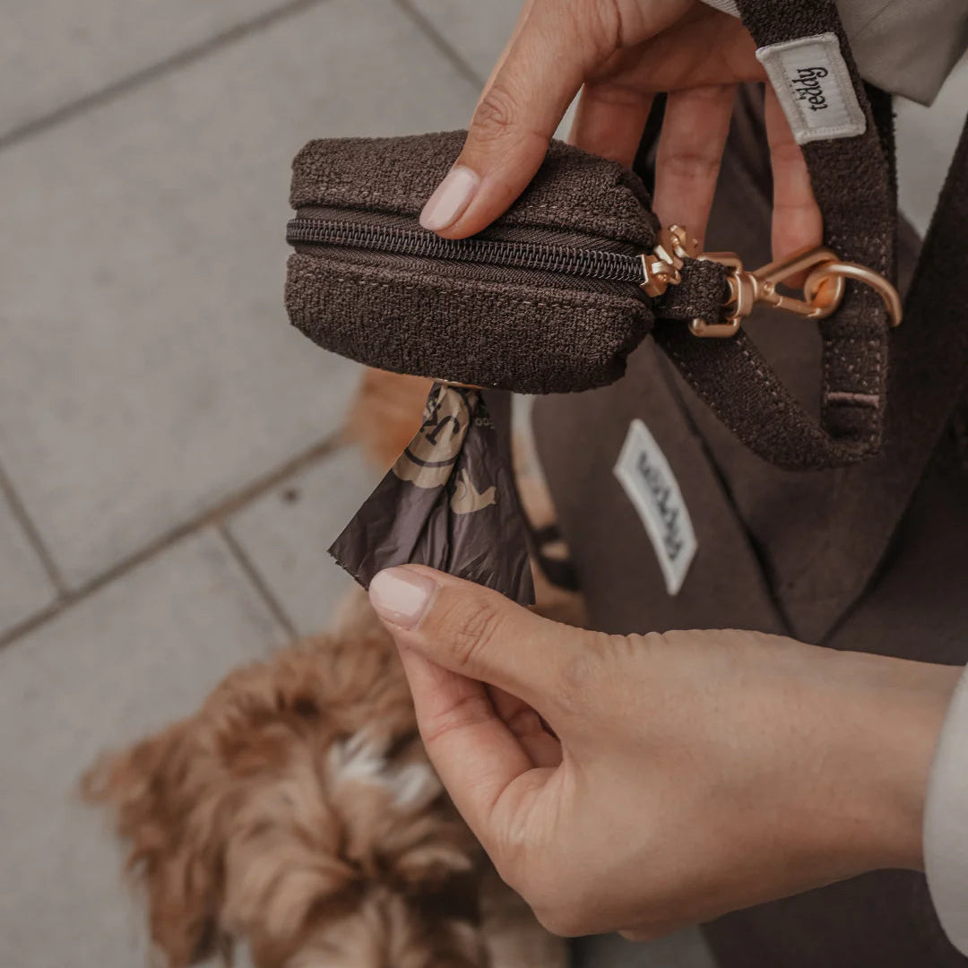 Person holding a brown textured wallet with a dog in the background