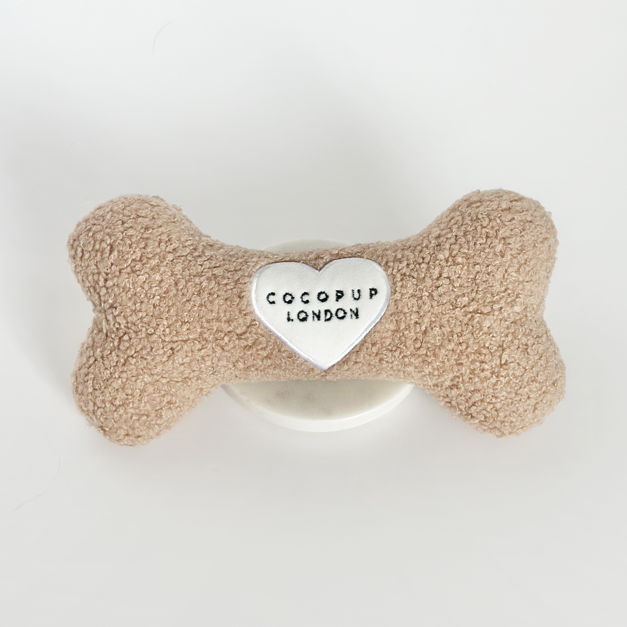 Dog bone-shaped toy with a heart-shaped tag displaying 'CocoPup London' on a white background