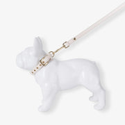 White dog-shaped object with a gold leash on a white background
