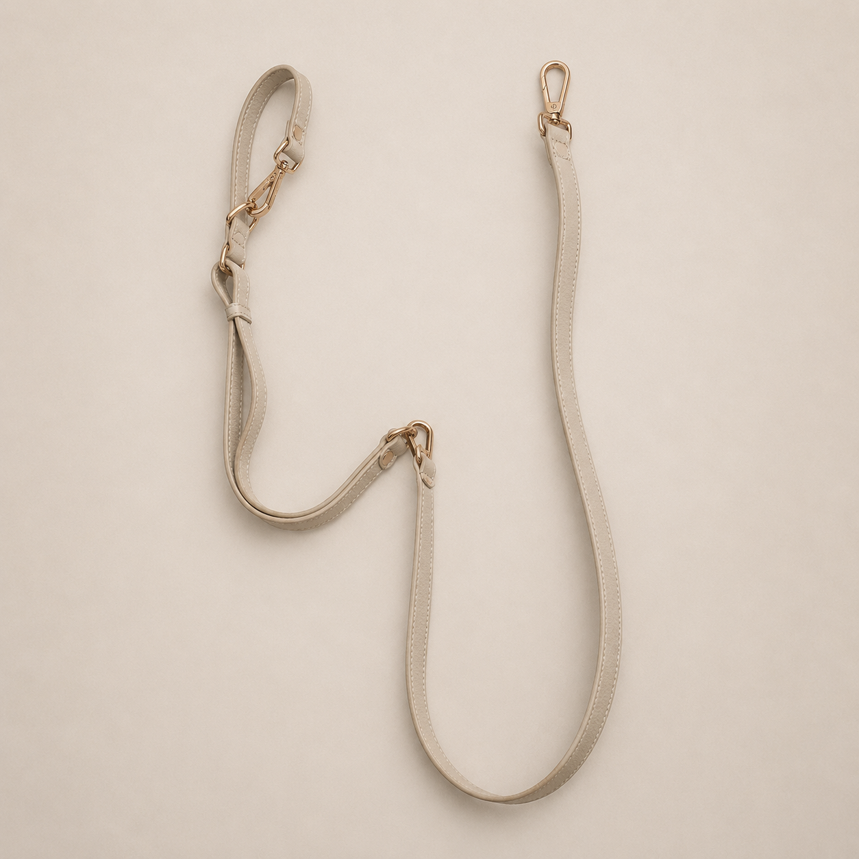 Beige bag strap with gold hardware on a beige background