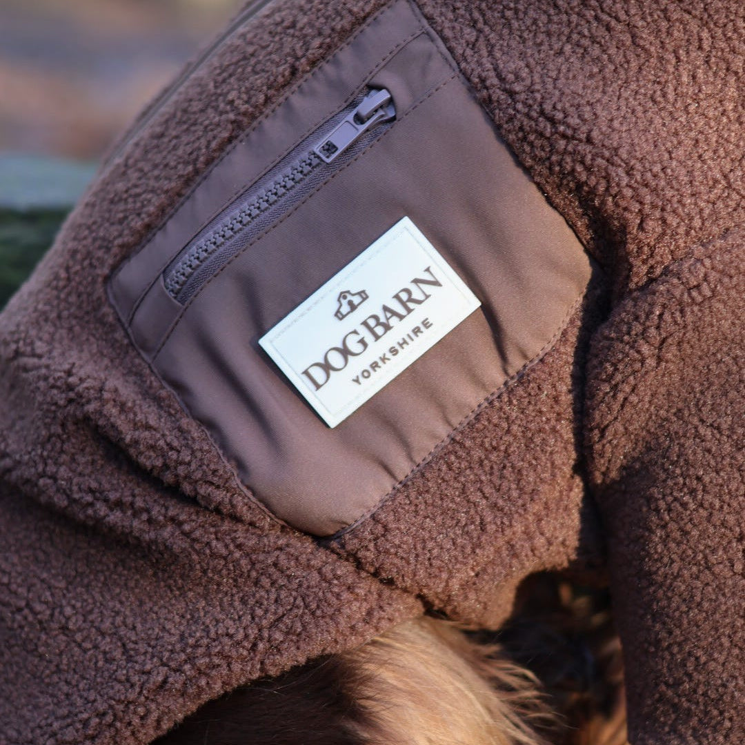 Brown fleece jacket with a visible Dogbarn logo on a blurred natural background