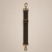 Black strap with gold hardware on a beige background