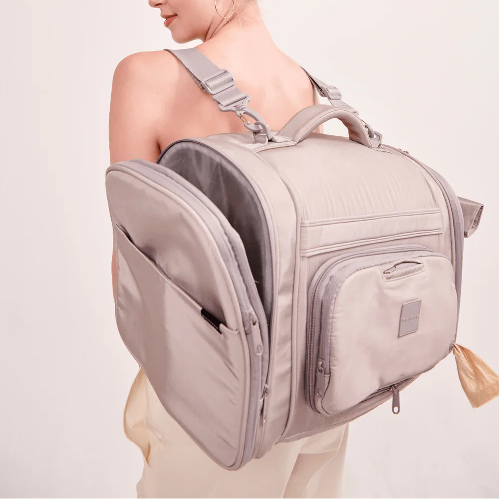 Woman wearing a beige backpack with a plain background