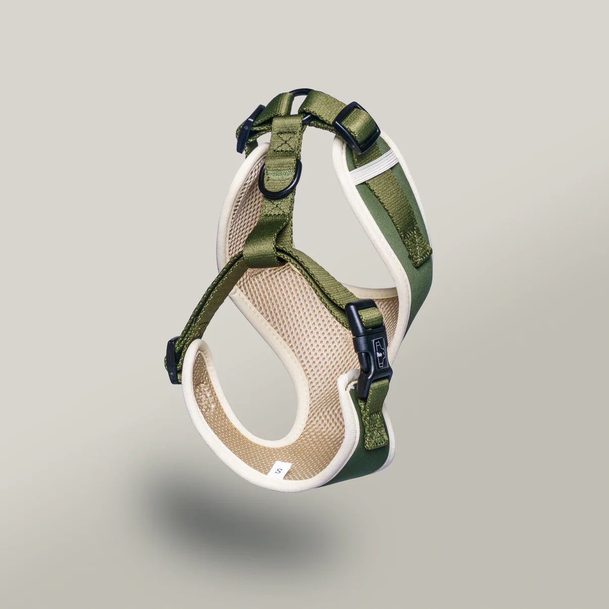 Green and beige dog harness on a light gray background