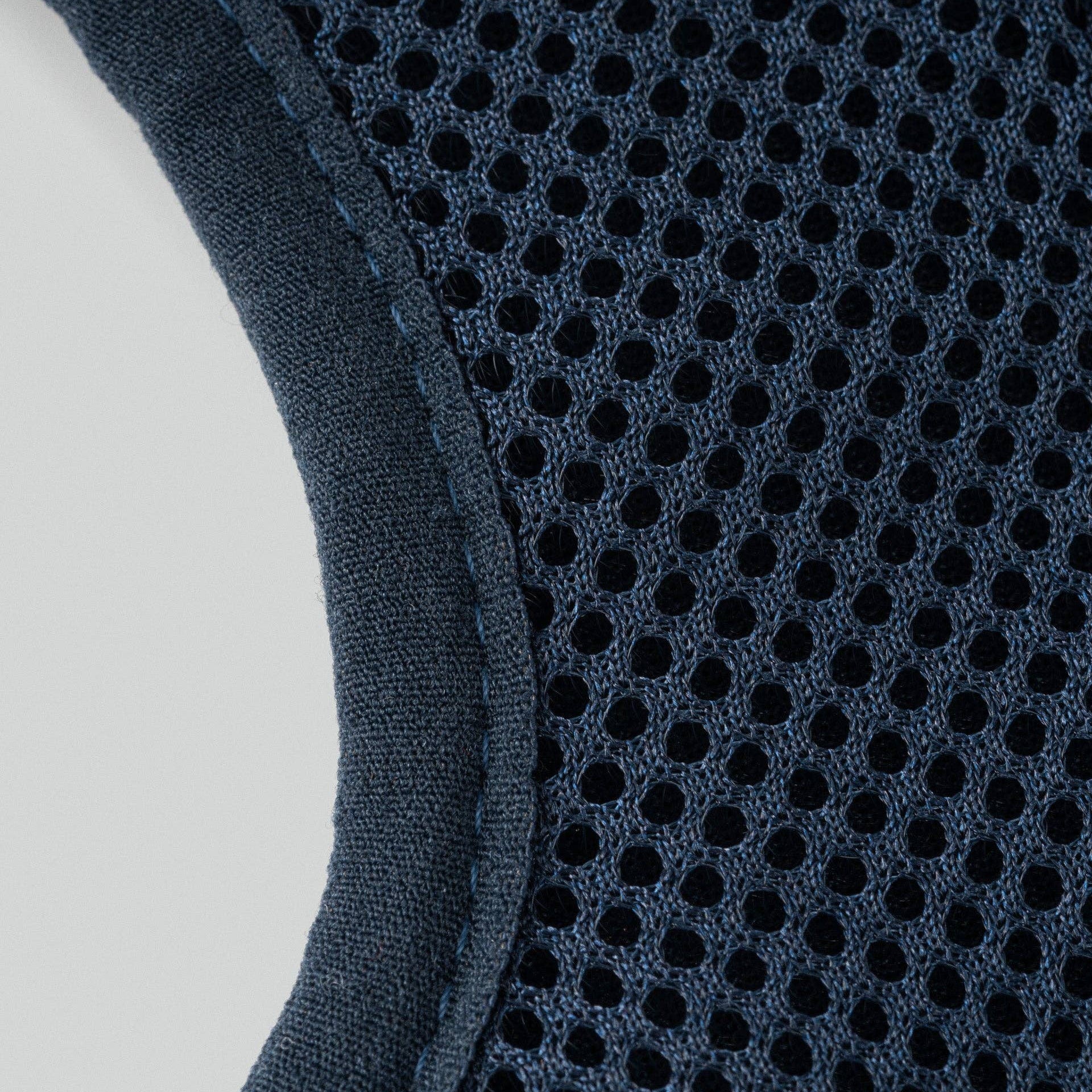 Close-up of a dark blue mesh fabric with a light gray background