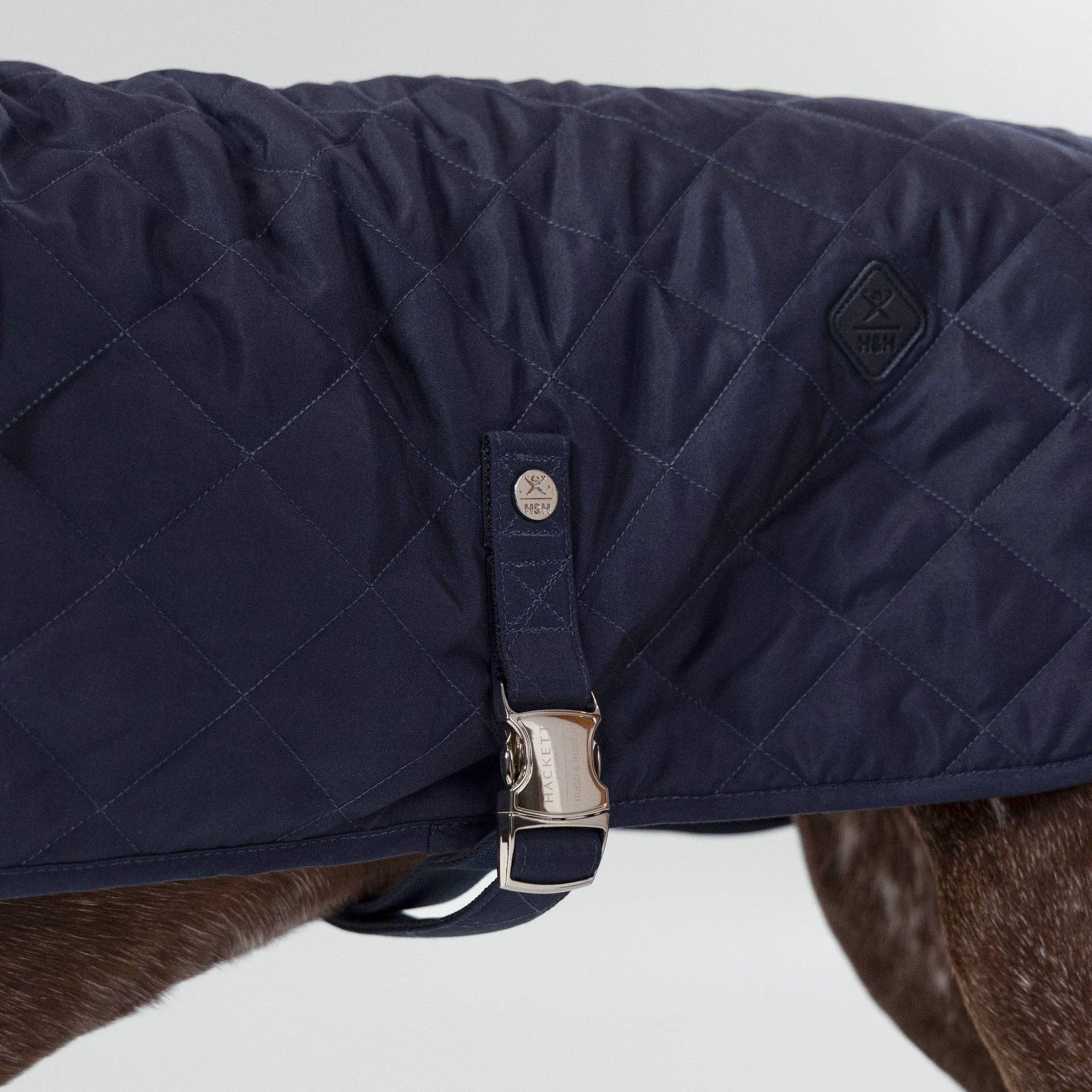 Close-up of branded rivet and buckle detail on the Navy Quilted Dog Jacket