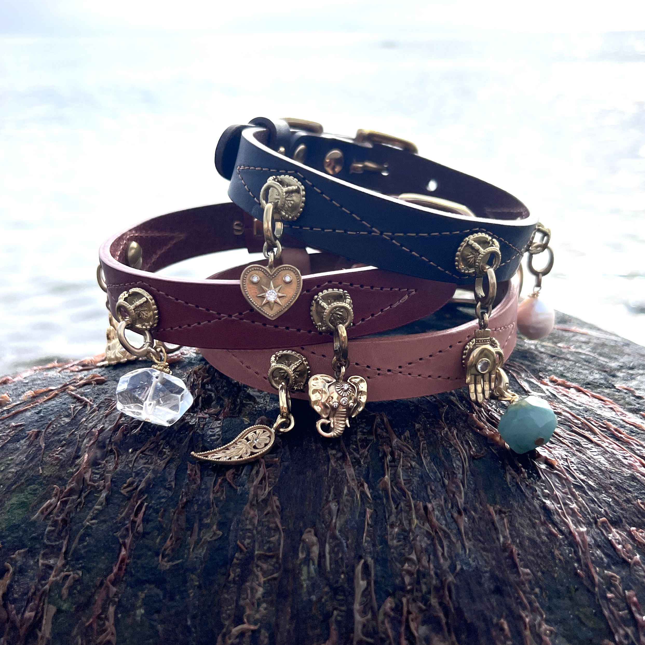 Two leather dog collars with charms on a wooden surface