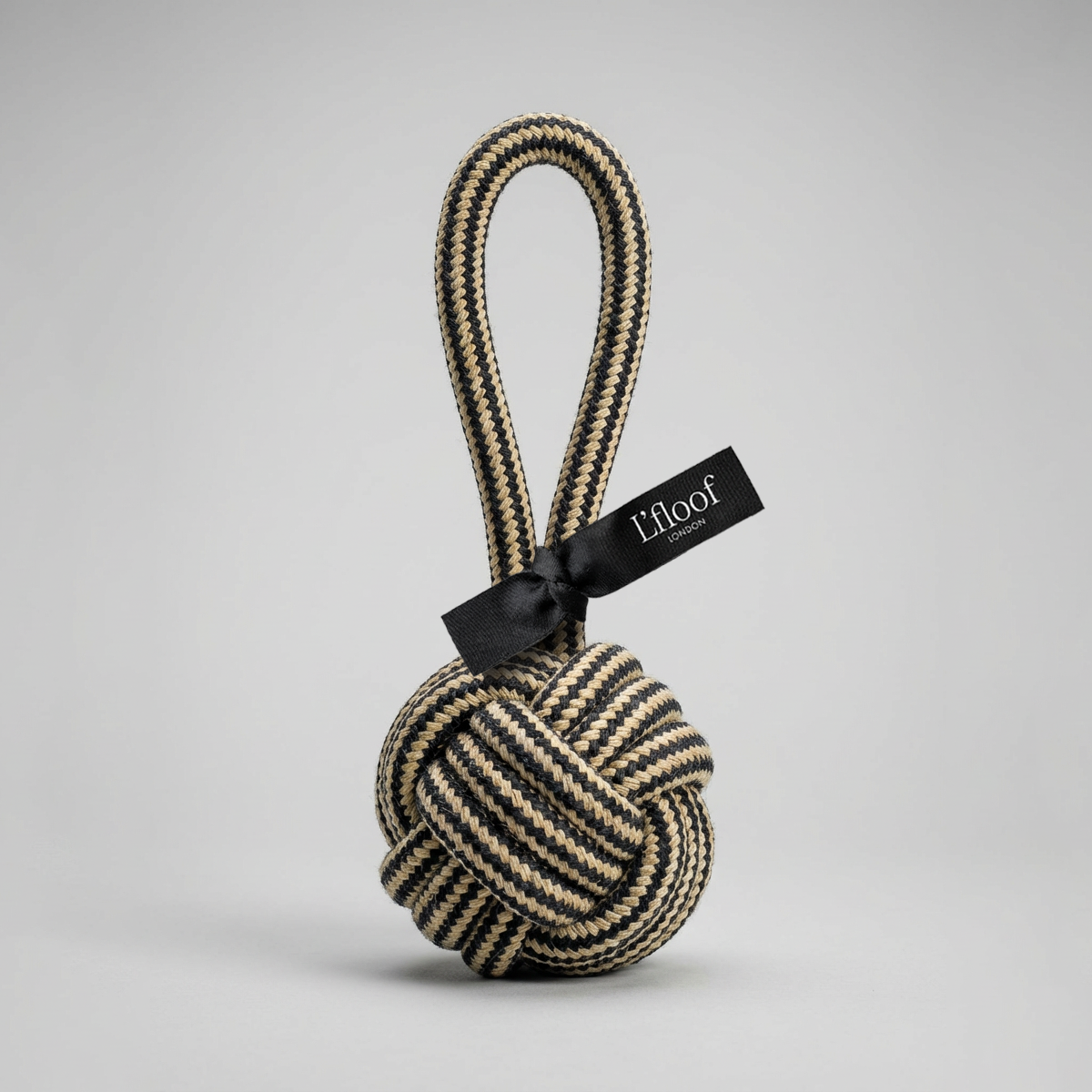 Textured ball with rope and black tag on a light gray background