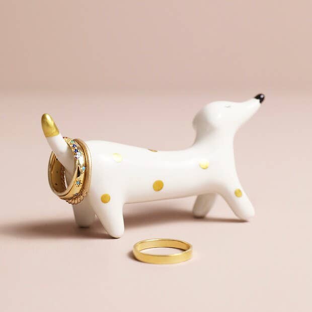 Ceramic sausage dog ring holder styled on a bedside table