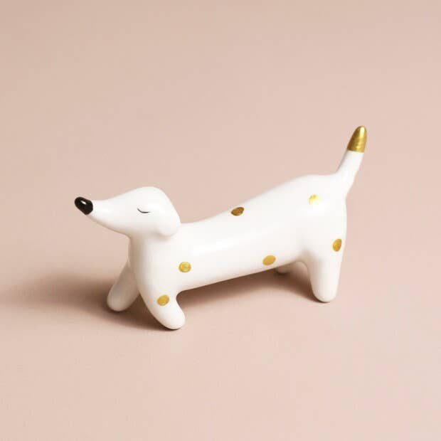White dog figurine with gold spots on a beige background