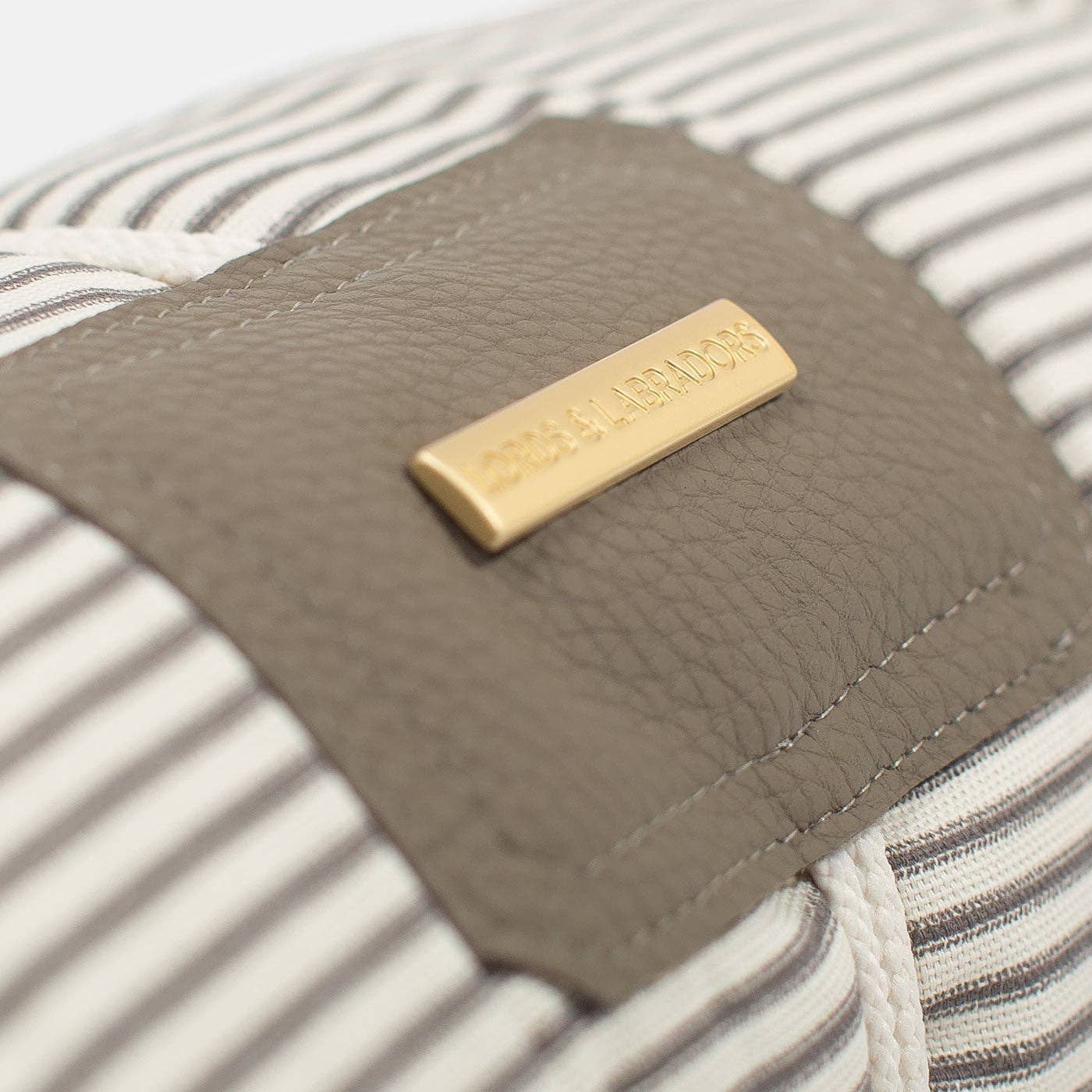 Close-up of a brown leather wallet with a gold tag on a striped fabric background