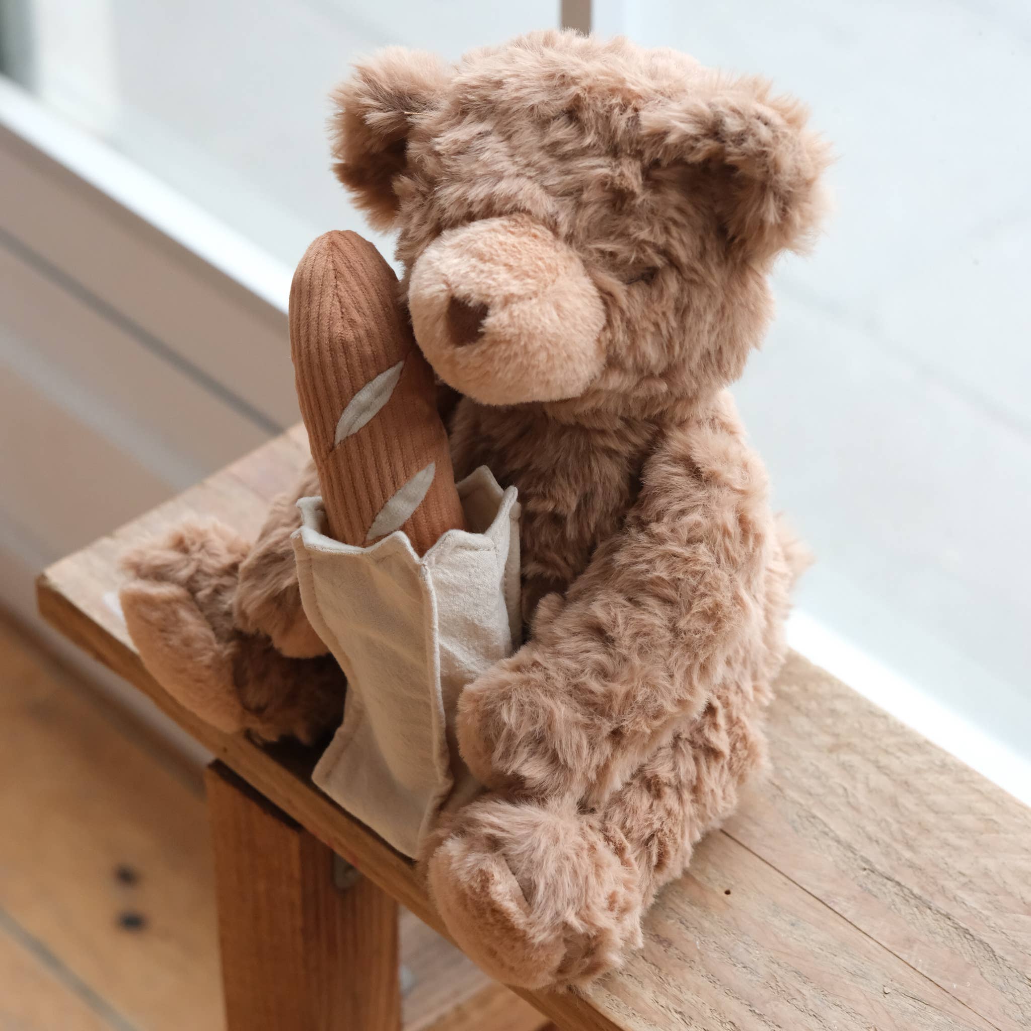 Brown teddy bear holding a brown toy on a wooden surface with a light background