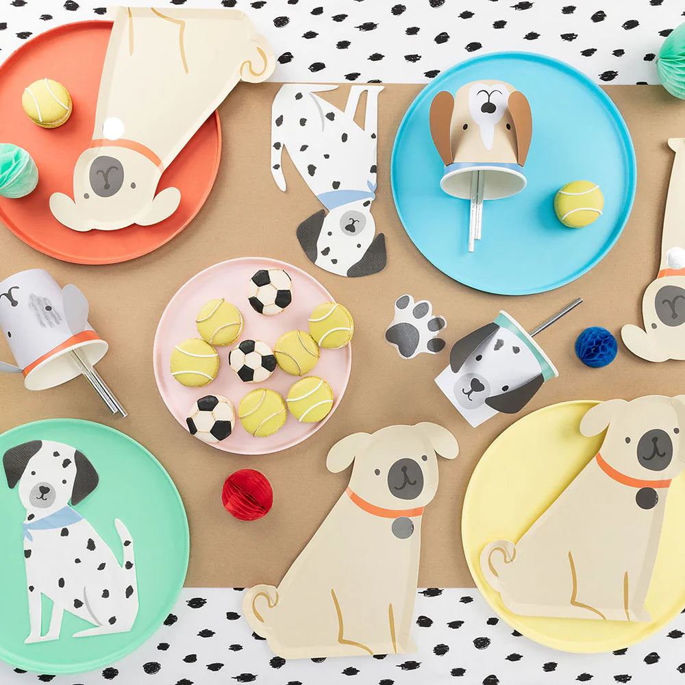 Children's party table with dog-themed plates, cups, and decorations on a polka dot tablecloth.