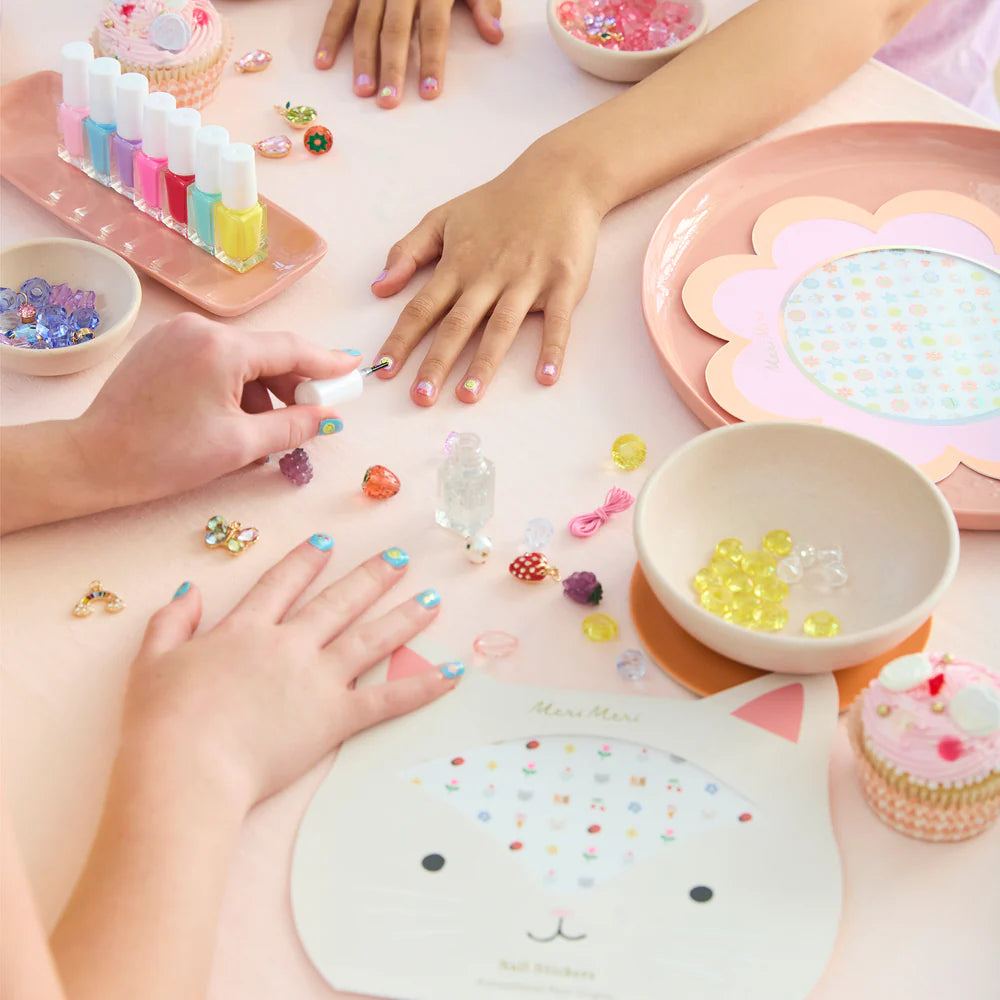 Children's hands engaging in a nail art activity with colorful decorations on a table.