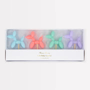 Set of colorful balloon dog-shaped candles in a box on a white background