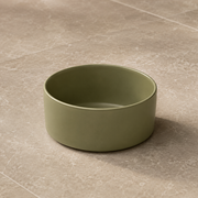 Green ceramic bowl on a beige tiled floor