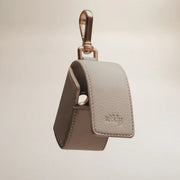 Beige leather keychain case with gold clasp on a beige background
