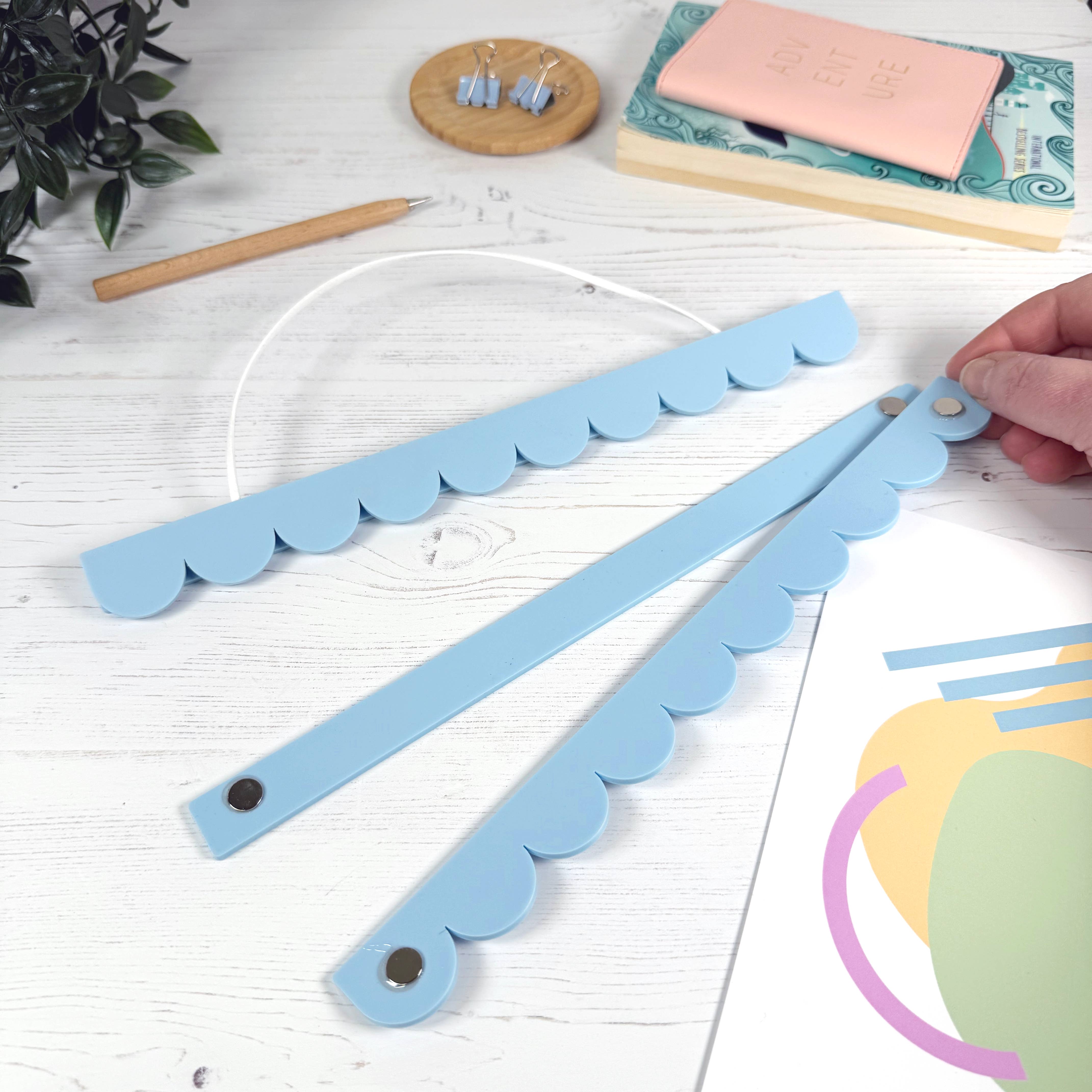 Blue decorative item with scalloped edges on a white surface with stationery items.