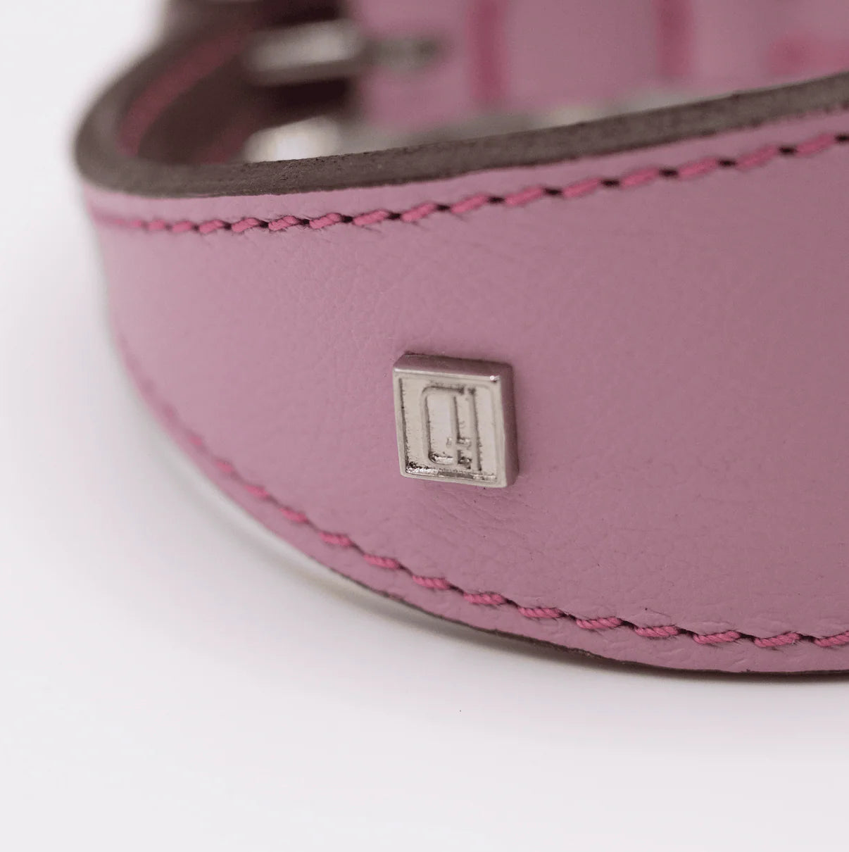Close-up of a pink leather belt with a metal buckle on a white background