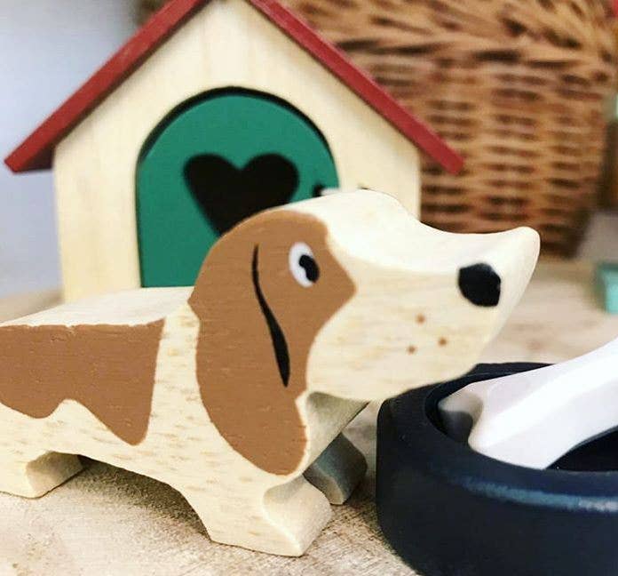 Wooden dog toy with a heart-shaped door and a wicker basket in the background.