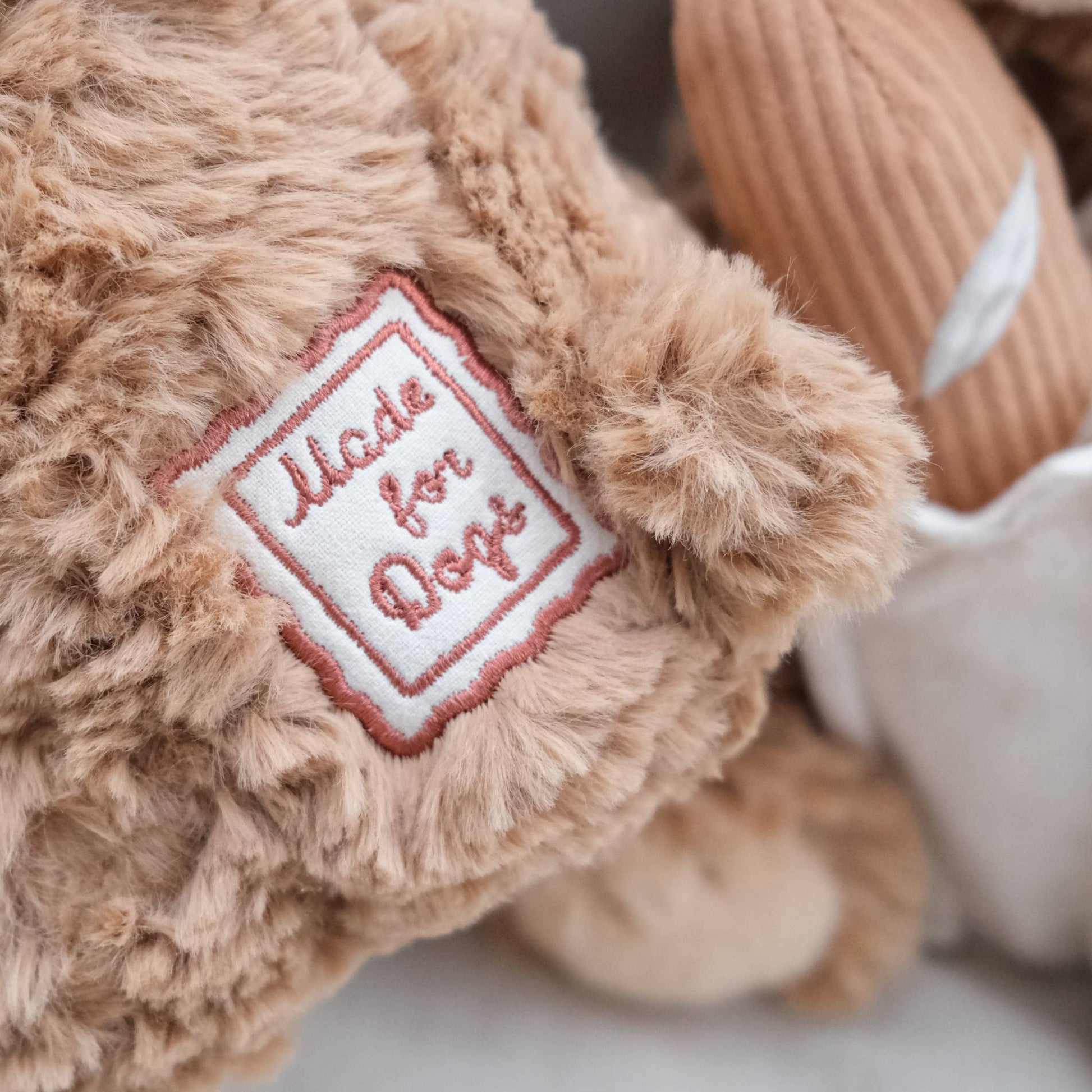 Close-up of a plush toy with a 'Made for Dogs' label on a soft background